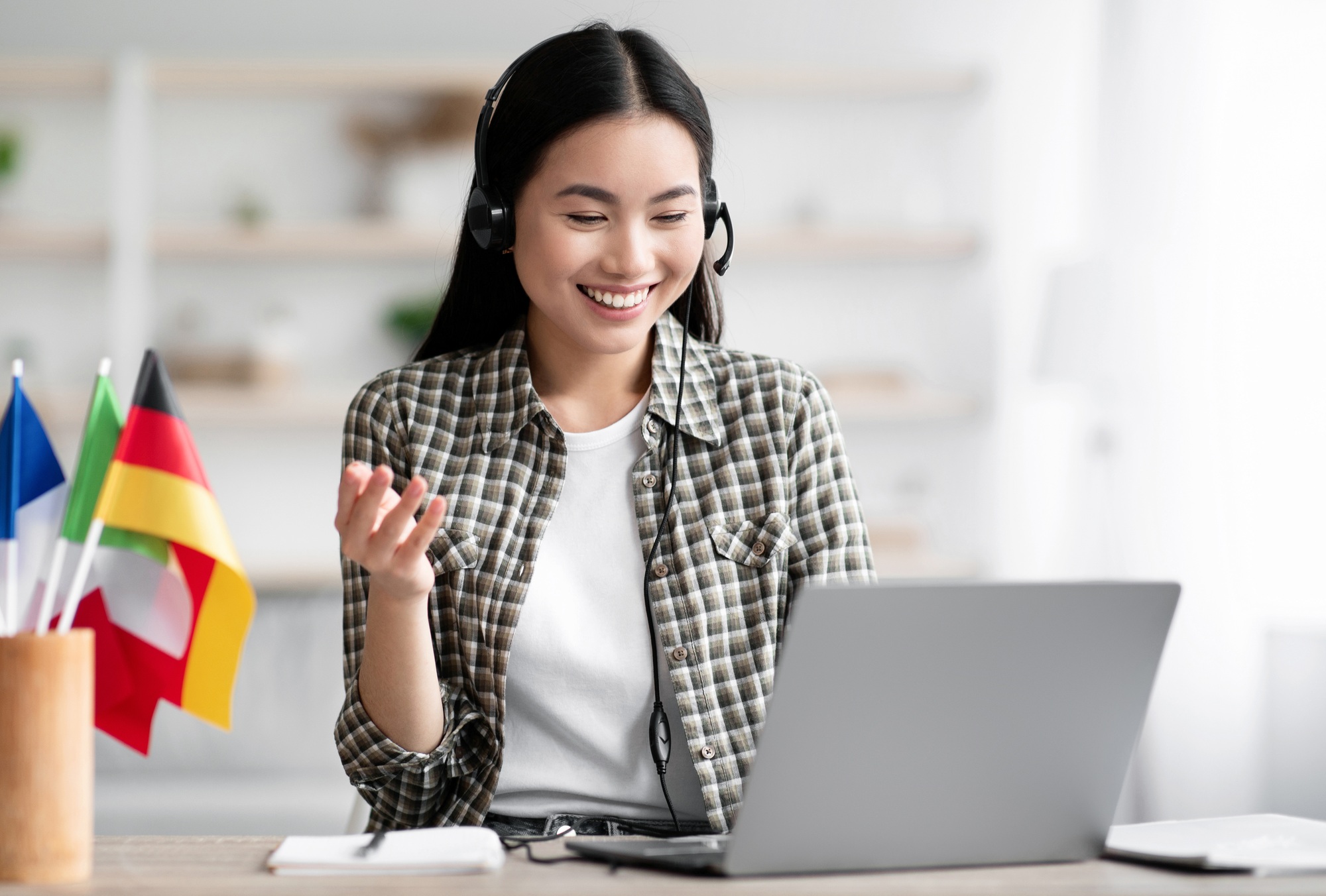 Happy asian lady using laptop and headset, learning foreign language