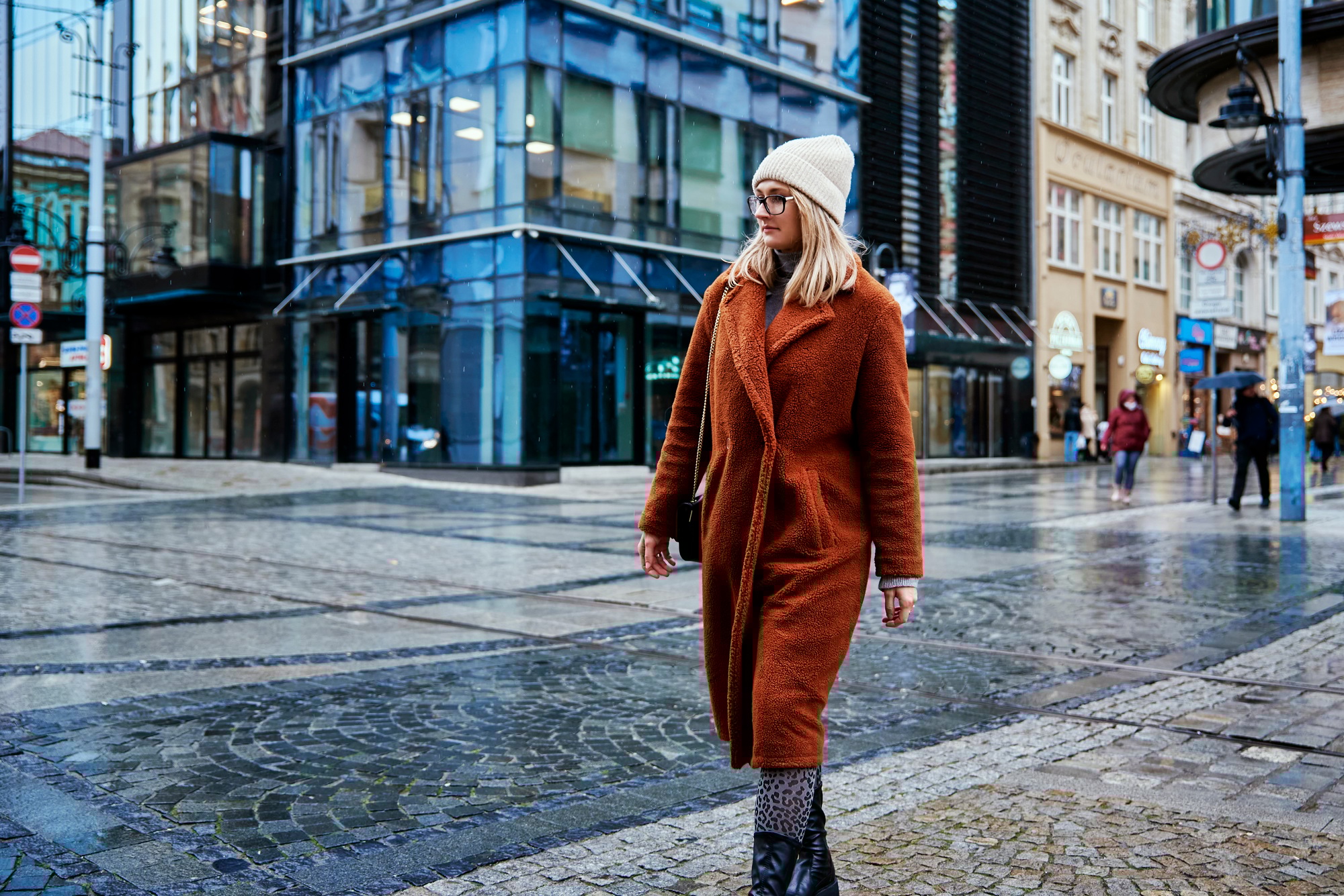 Woman walking on city street with numerous store signs illustrating visual language.