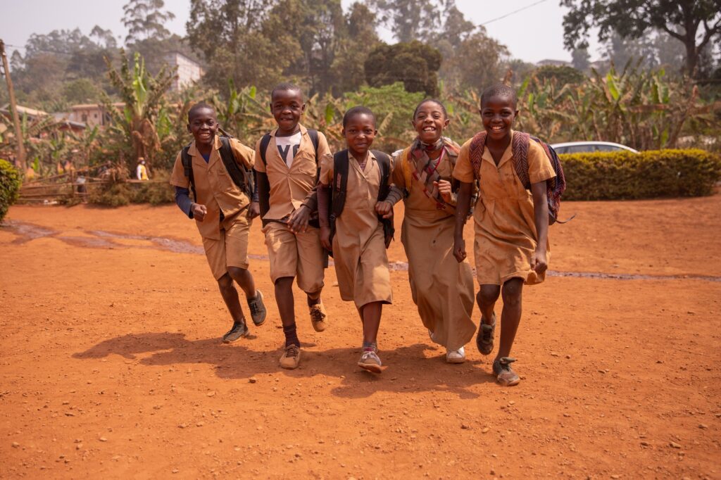 Young group of african children all together at school yard having fun playing holding hands after language lessons.