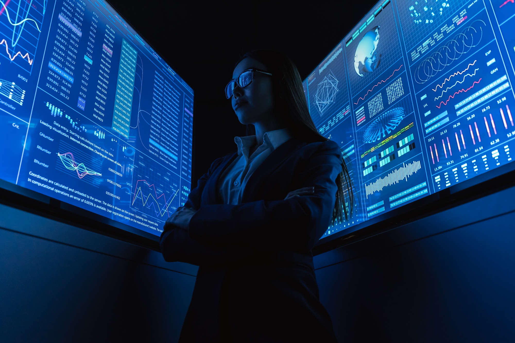 The businesswoman standing near the blue monitor.
